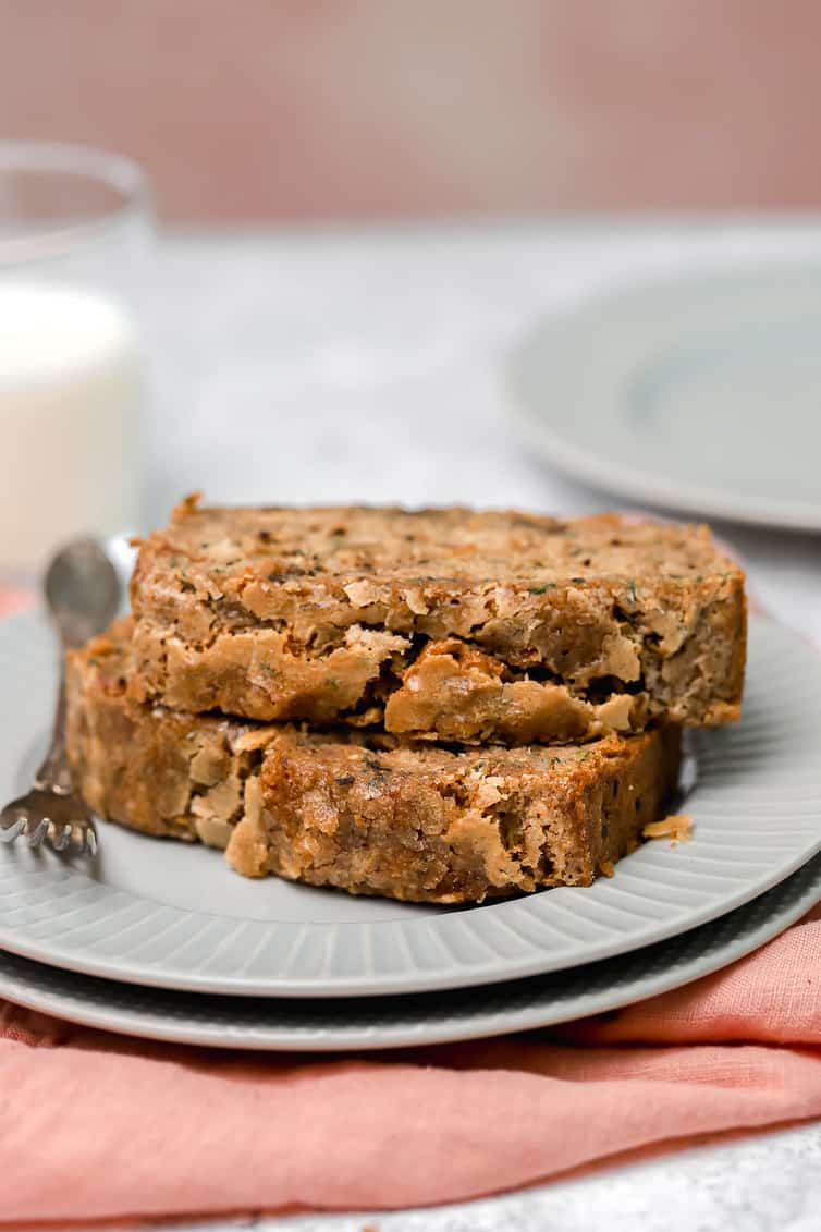 Two slices of zucchini bread stacked on together on white plate.
