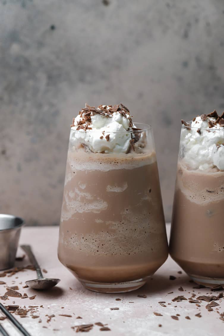 Two glasses of frozen hot chocolate topped with whipped cream and chocolate shavings.