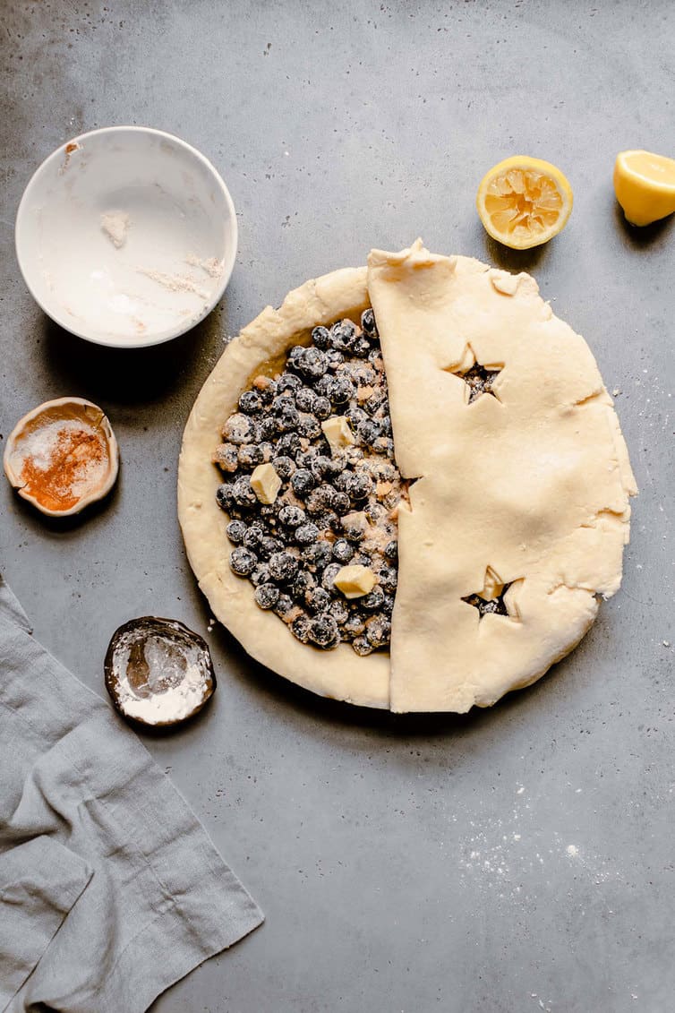 Blueberry pie filling half covered with pie crust.