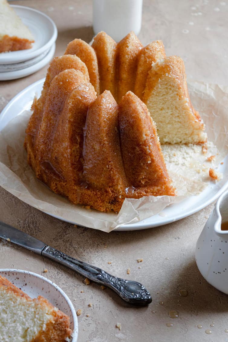 A Bundt-style butter cake on a serving platter with slice removed.