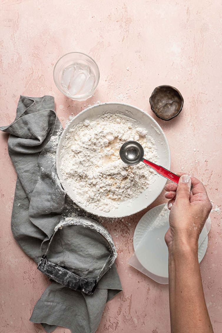 Adding ice water to pie crust.