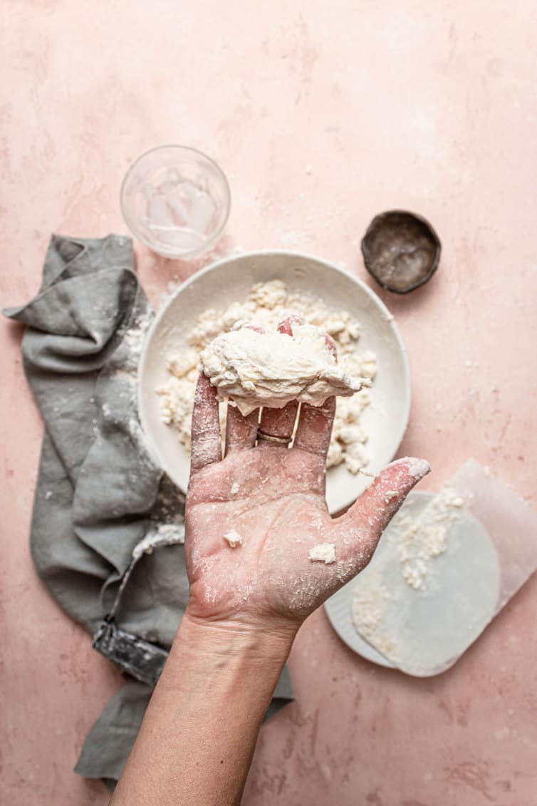 Squeezing pie crust dough in hand.