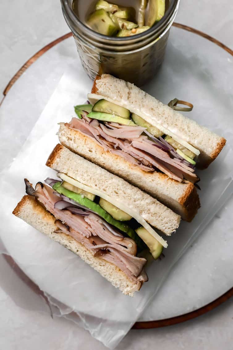 Sandwich with a jar of pickles in the background.