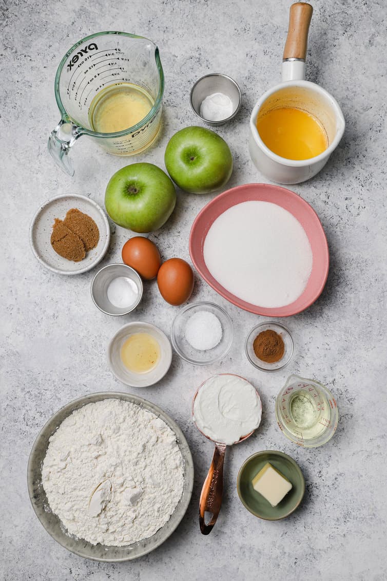 Ingredients for apple muffins prepped in bowls on counter.