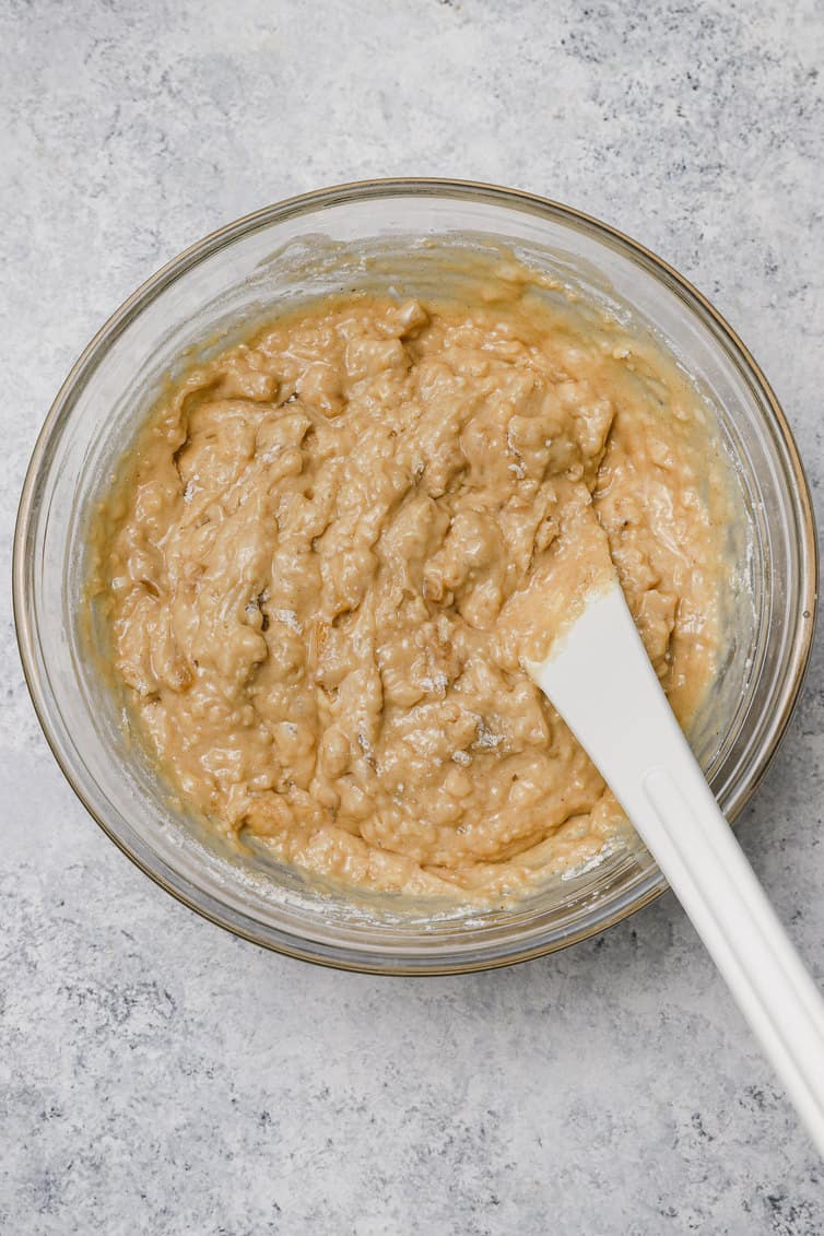 Apple muffin batter mixed together in a glass bowl.