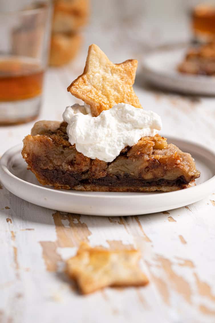 A slice of derby pie on a plate topped with whipped cream.