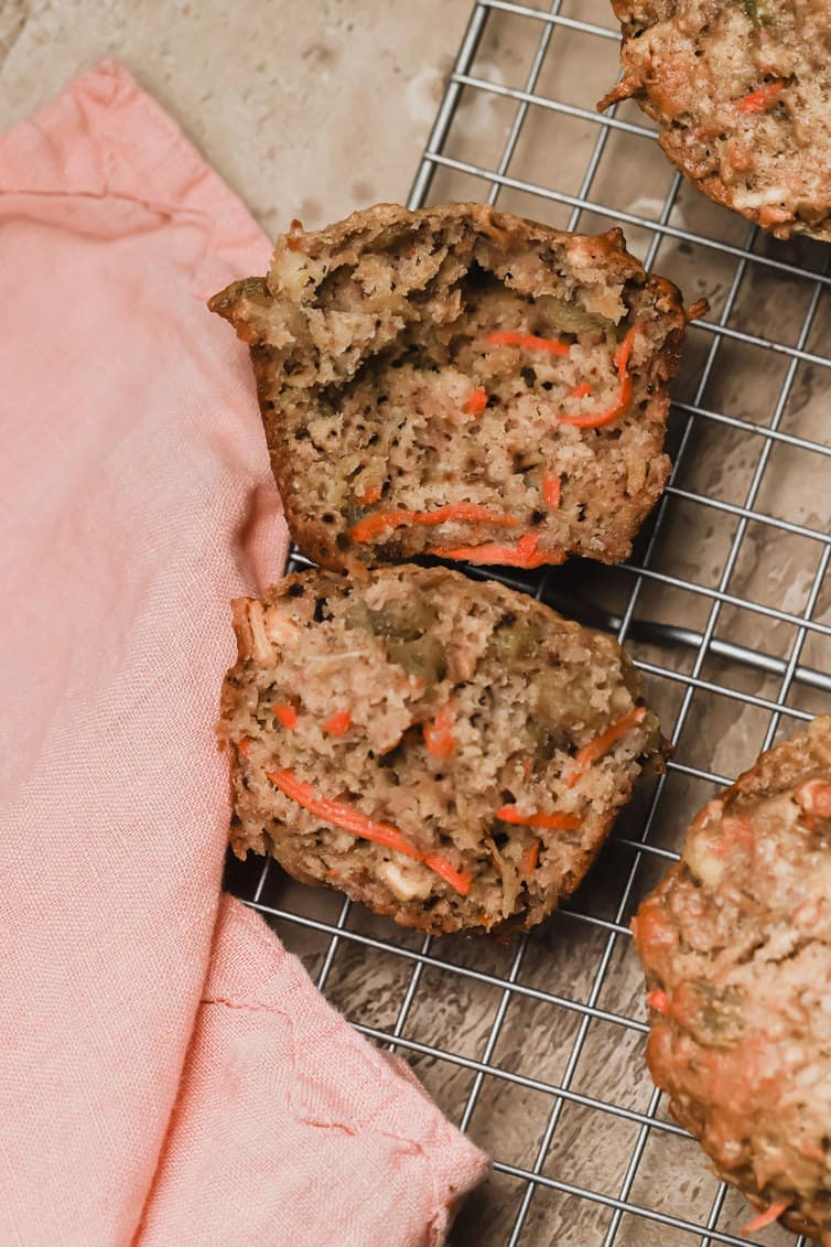 A morning glory muffin split in half on a wire cooling rack.