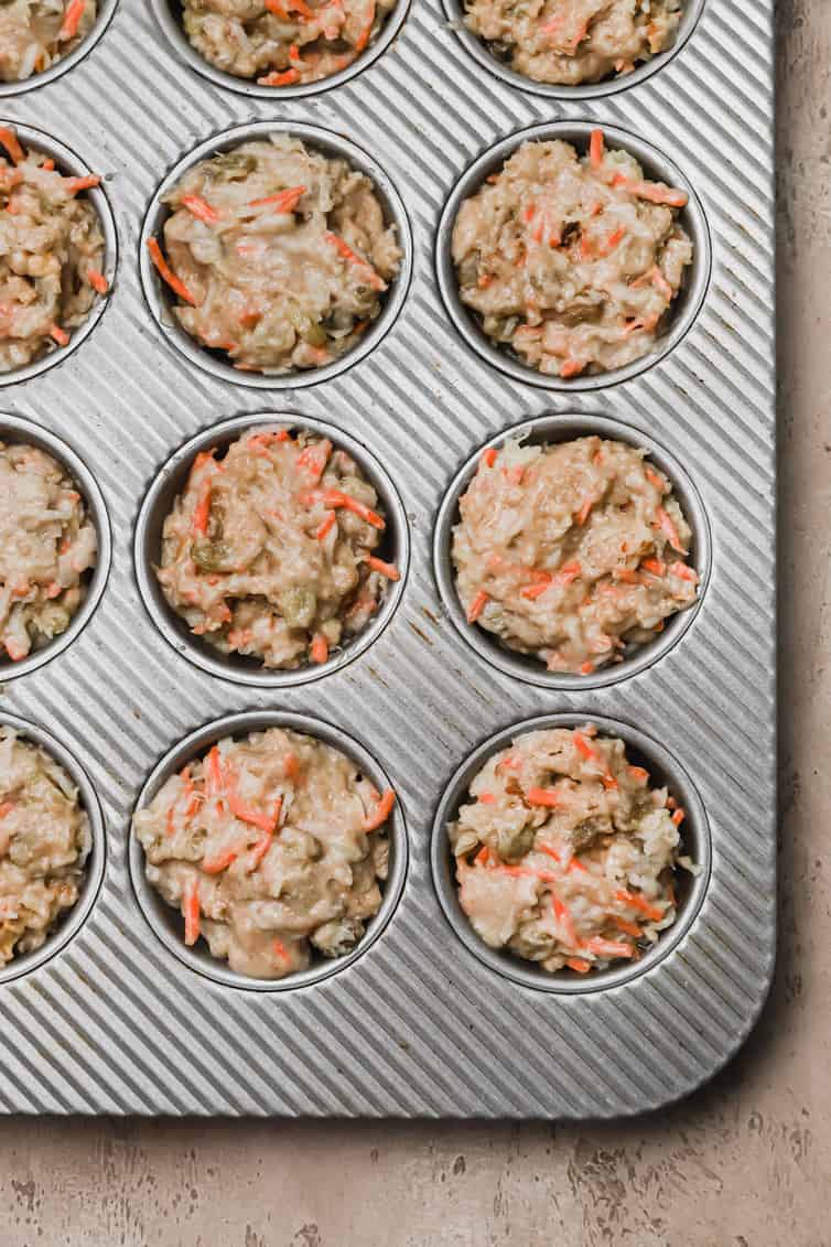 Morning glory muffin batter in a muffin pan before baking.