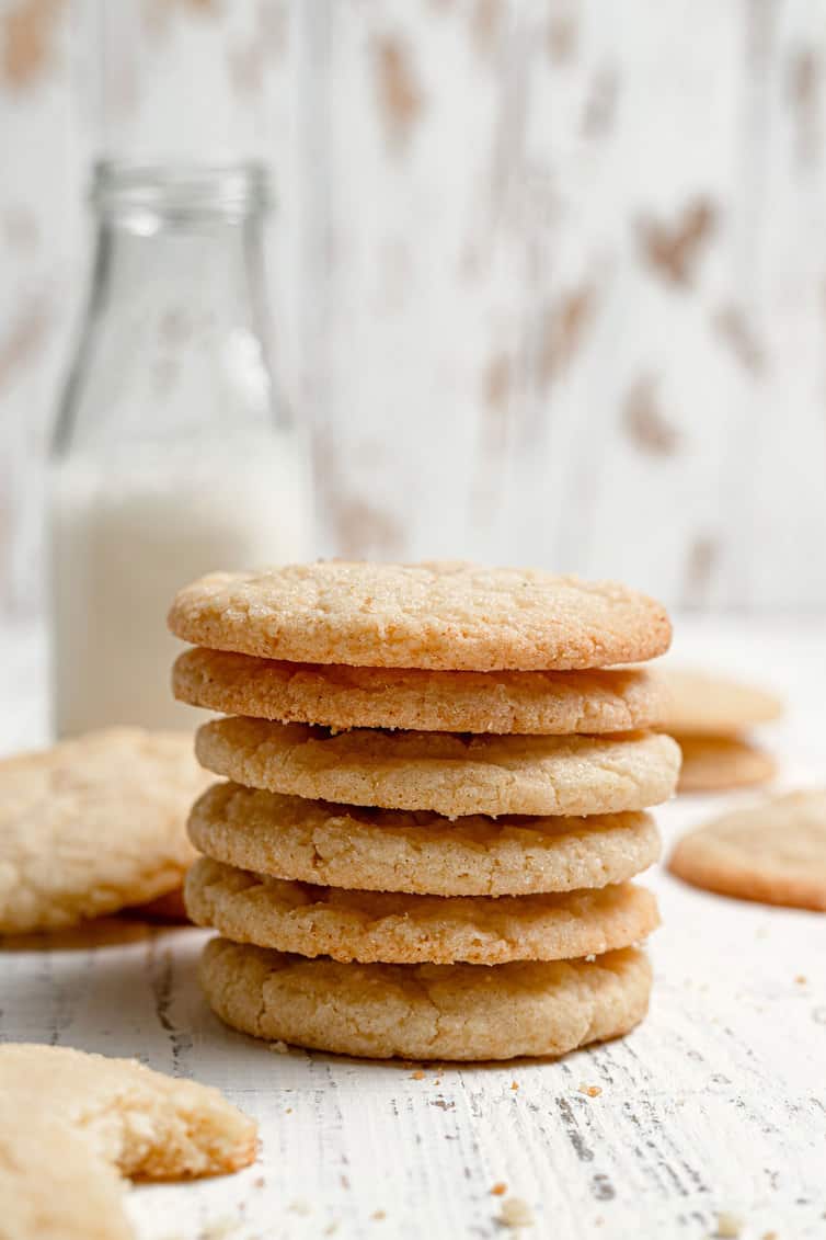A stack of sugar cookies with a bottle of milk in the background.