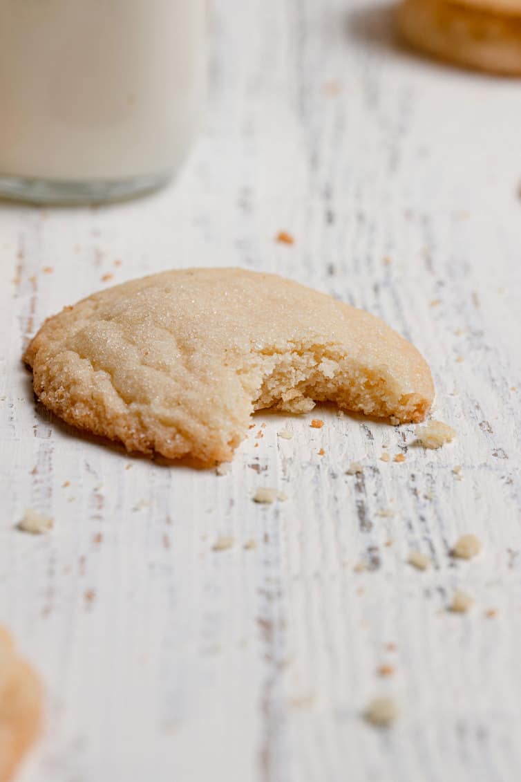 A single sugar cookie with a bite taken out of it.