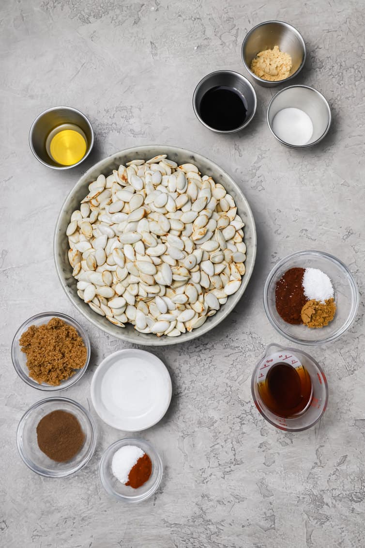 Ingredients for roasting pumpkin seeds prepped in bowls on a counter.