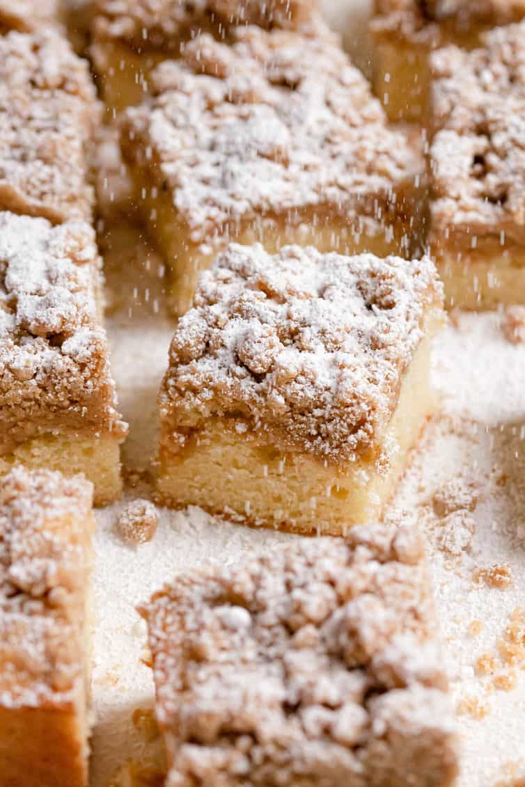 Crumb cake squares being sprinkled with powdered sugar.