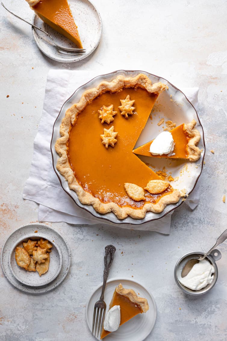 Overhead photo of pumpkin pie with sliced cut out and whipped cream on top.