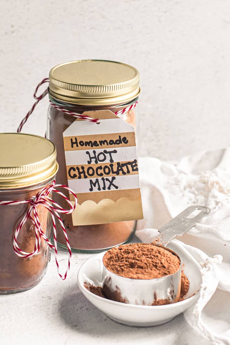 Homemade hot chocolate mix in jars and a scoop of it on a plate.