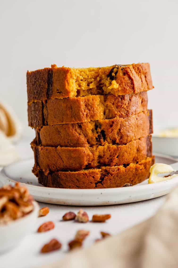 Slices of pumpkin bread stacked on a plate.