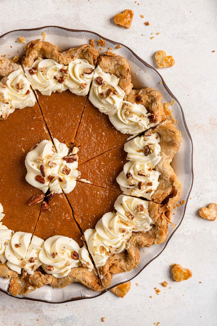 Overhead photo of sweet potato pie cut into slices with whipped cream and crushed pecans.