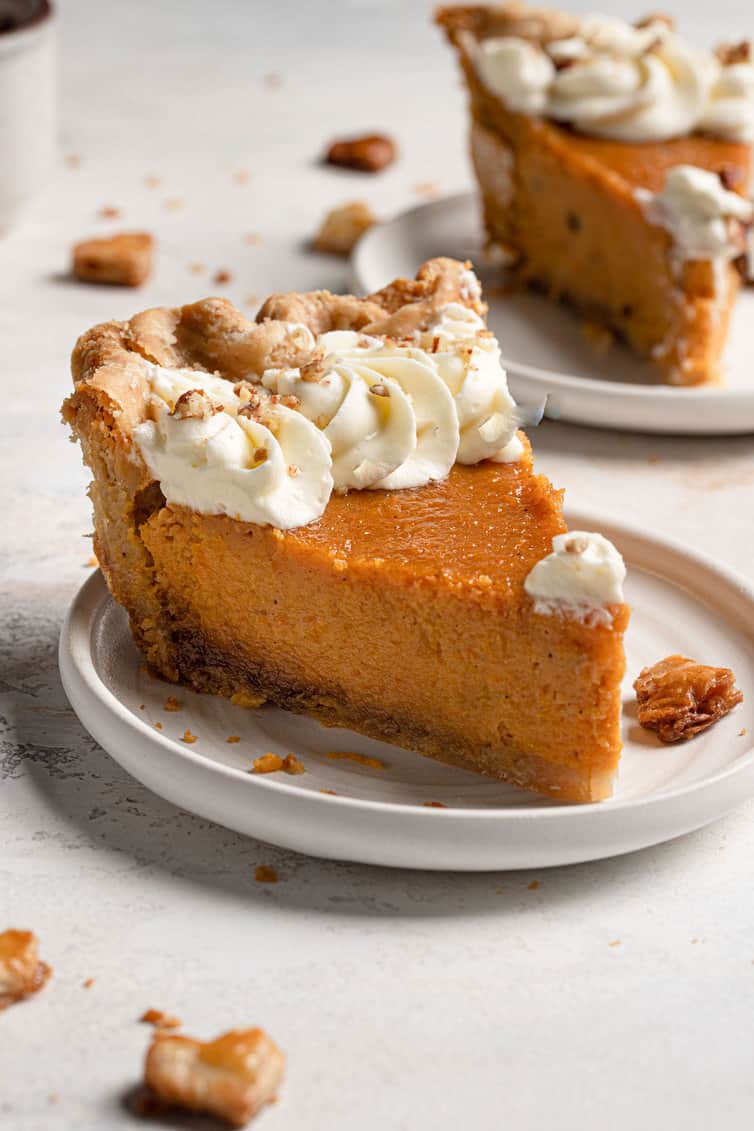 A slice of sweet potato pie with whipped cream and crushed pecans.