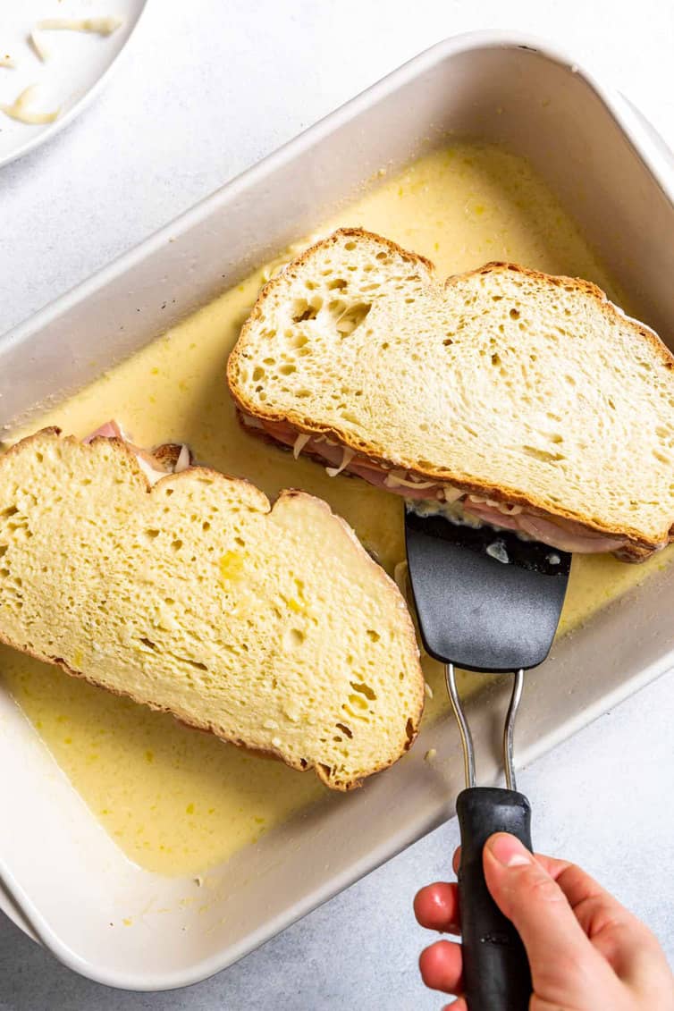 Flipping assembled sandwiches in custard.