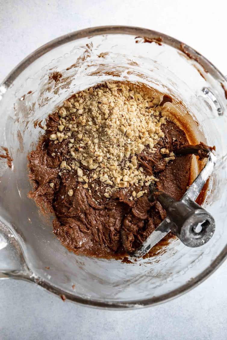 Nutella cookie dough in glass bowl with chopped hazelnuts on top.