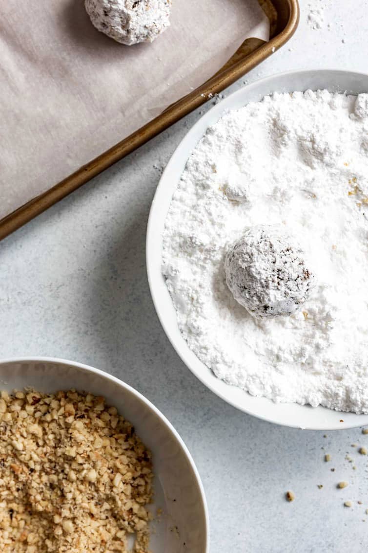 Rolling Nutella cookie dough ball in powdered sugar.