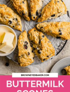 A circle of buttermilk scones on a cooling rack covered in parchment paper with a small bowl of butter slices to the left with the words Buttermilk Scones in white in a pink section at the bottom of the photo.