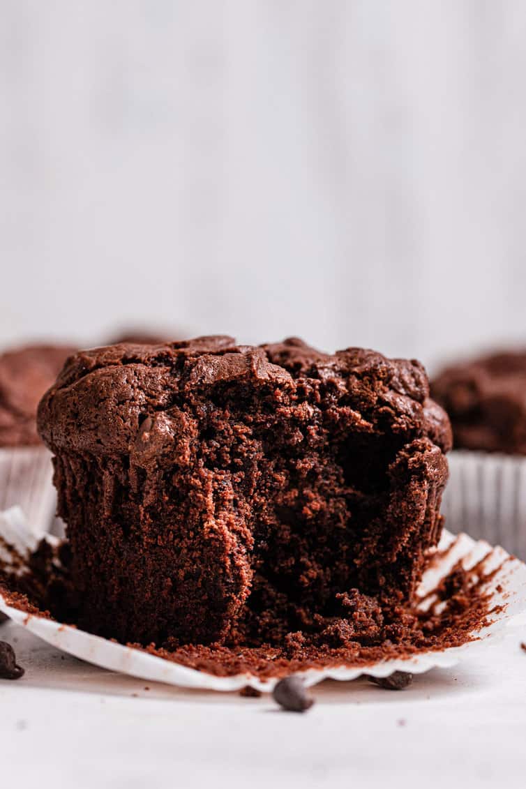 A chocolate muffin with a big bite taken out.