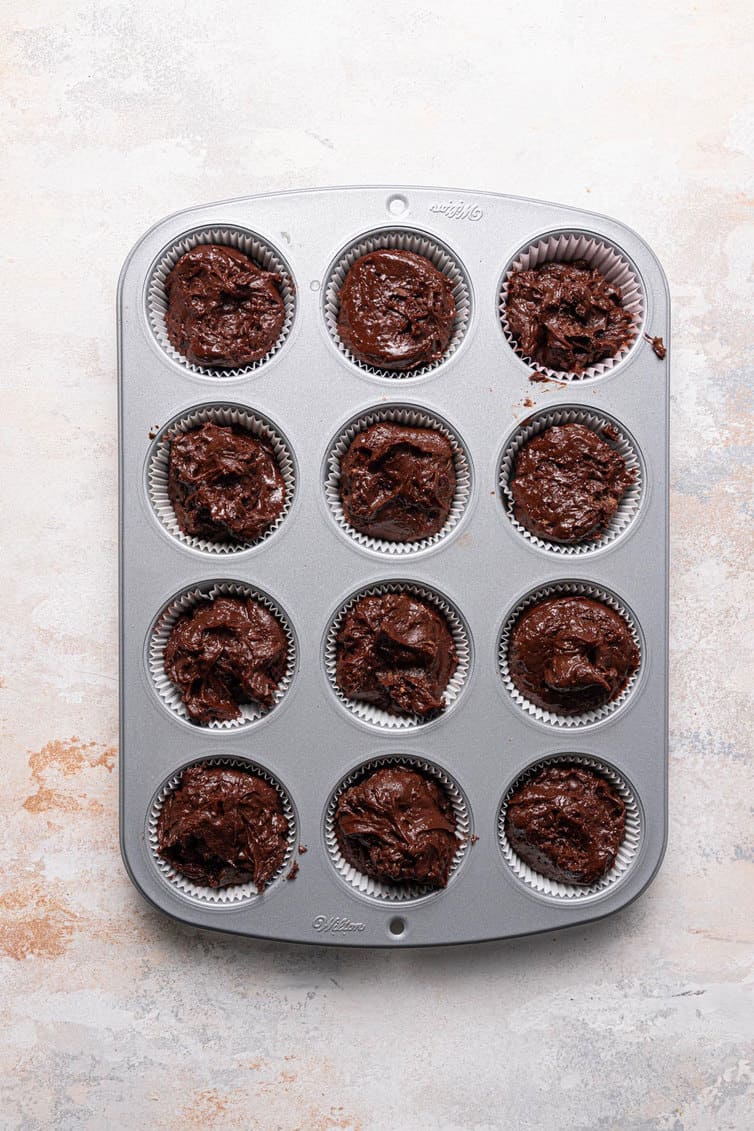 Chocolate muffin batter portioned into a muffin cup.