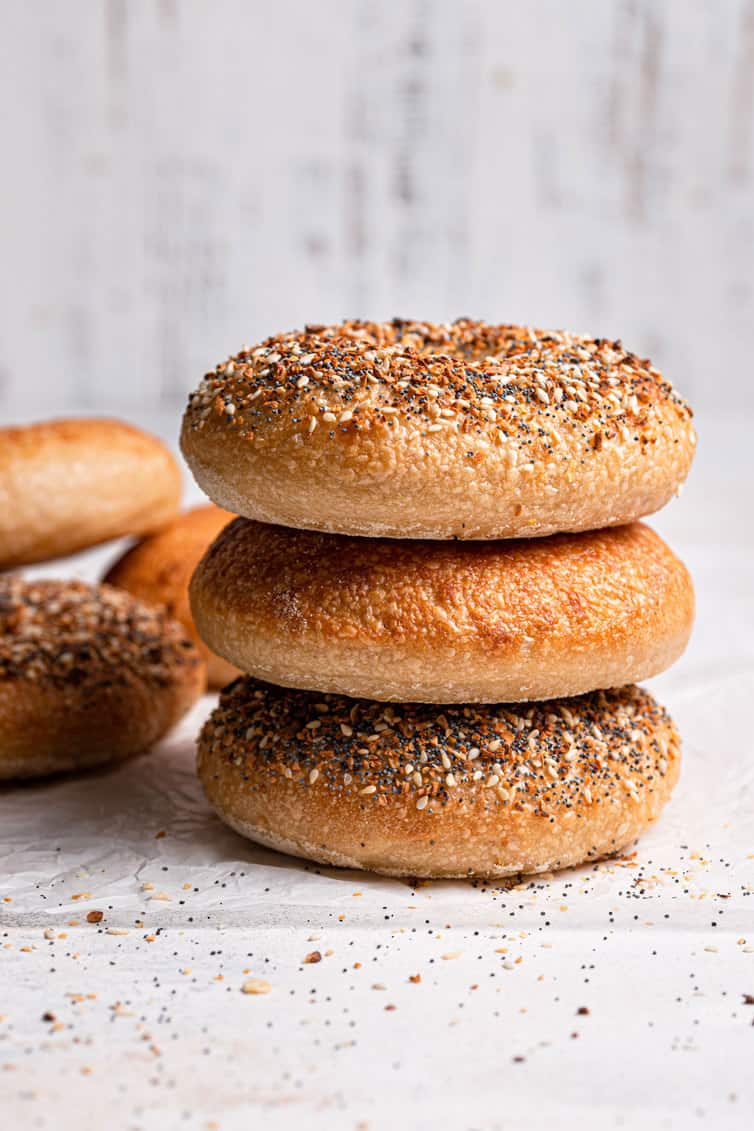 Stack of three bagels on a counter.