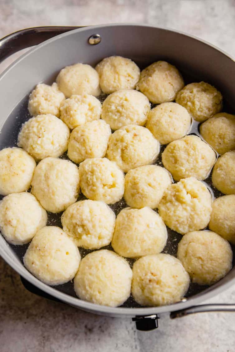 A single layer of matzo balls boiling in a pot.