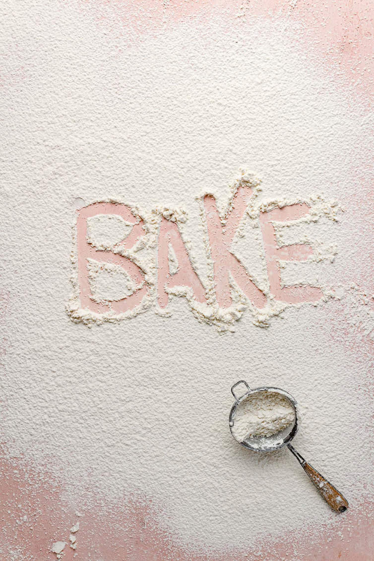 Flour dusted on a counter with the word "bake" traced in it.
