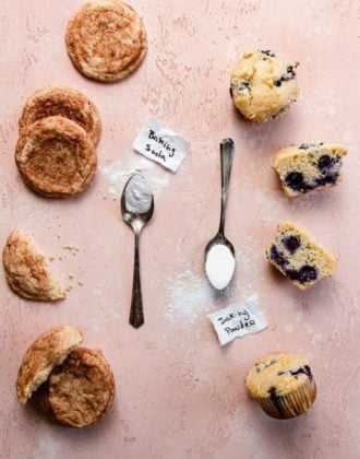 Snickerdoodle cookies and blueberry muffins with spoonfuls of baking soda and baking powder next to them.