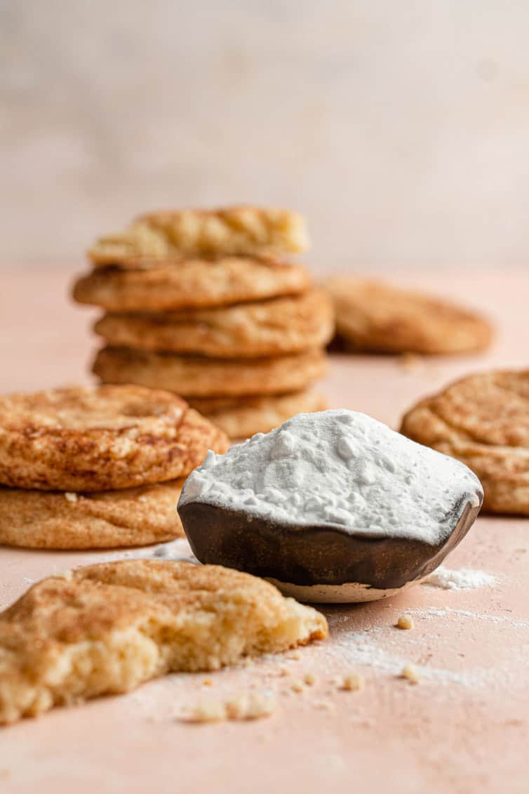 A scoop of baking soda surrounded by snickerdoodle cookies.