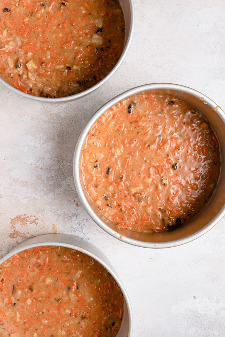 Carrot cake batter in three round cake pans.