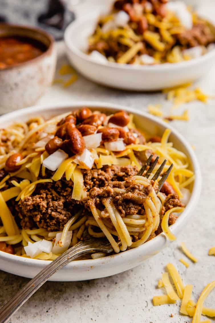 A fork twirling together spaghetti noodles with Cincinnati chili.