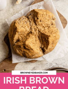 A loaf of Irish brown bread on parchment paper on a cutting board with a pink rectangle at the bottom with the words Irish brown Bread in whtie.
