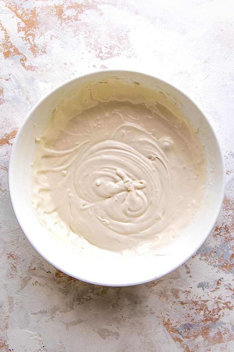A white bowl with the cream cheese filling for oatmeal cream pies.