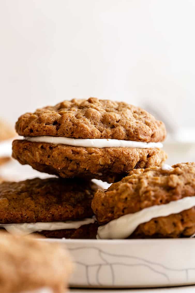 Three oatmeal cream pies on a white plate stacked with two on bottom and one on top.