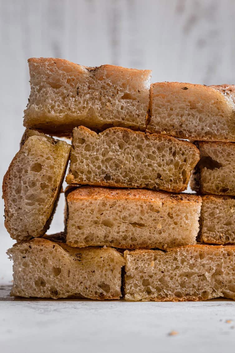 A stack of sliced focaccia layered like bricks on a white counter.
