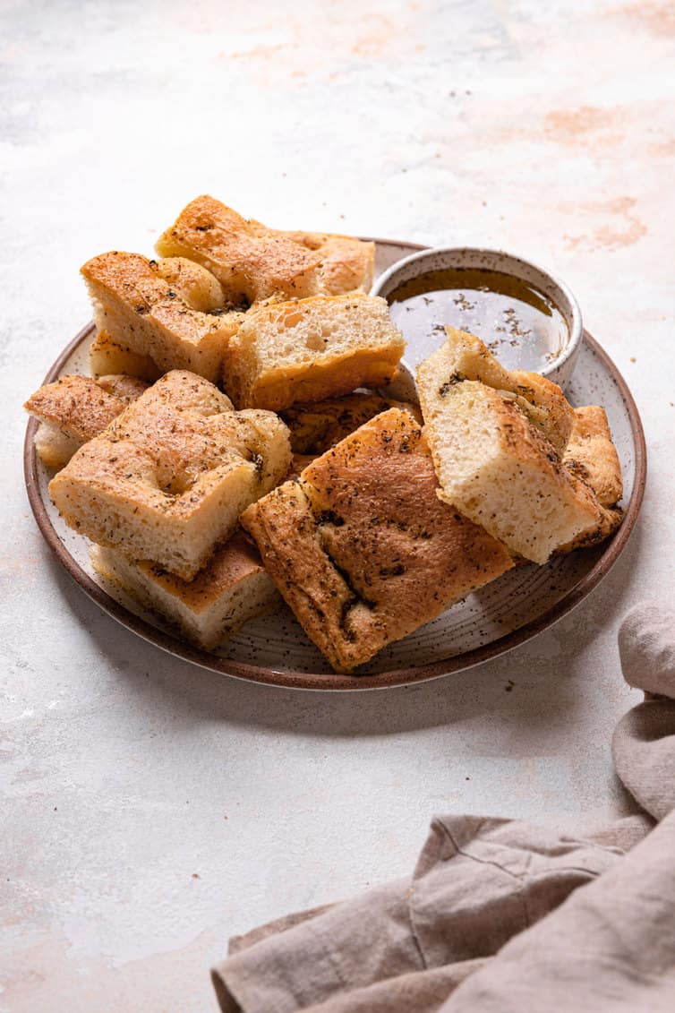 A small plate with sliced focaccia and a small bowl of herb oil.