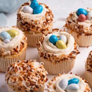 A square photo of coconut cupcakes topped with coconut frosting and toasted coconut.