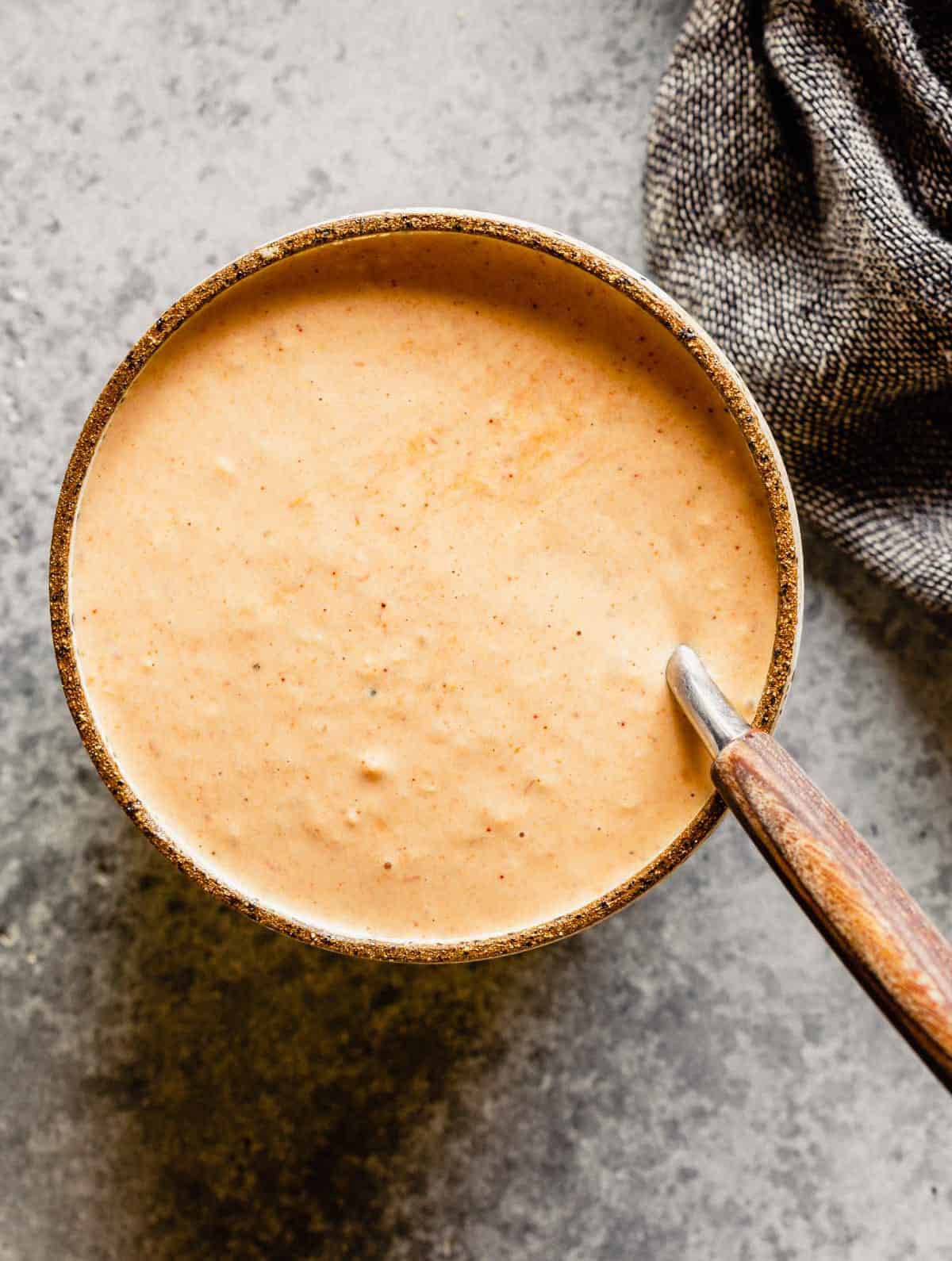 A bowl of Russian dressing that has been stirred with a spoon.