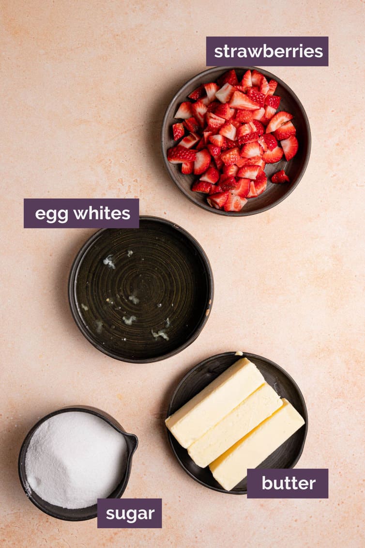 Ingredients for strawberry meringue frosting on a pink counter with purple labels.