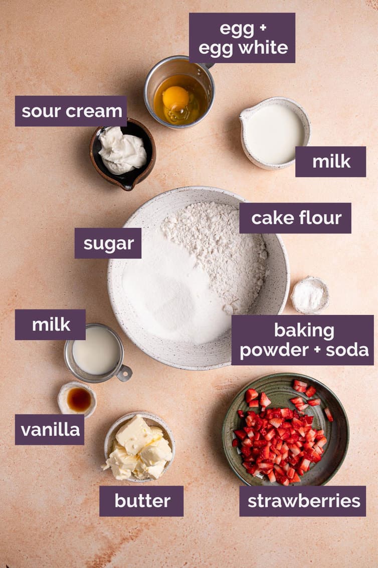 Ingredients for strawberry cupcakes on a pink counter with purple labels.