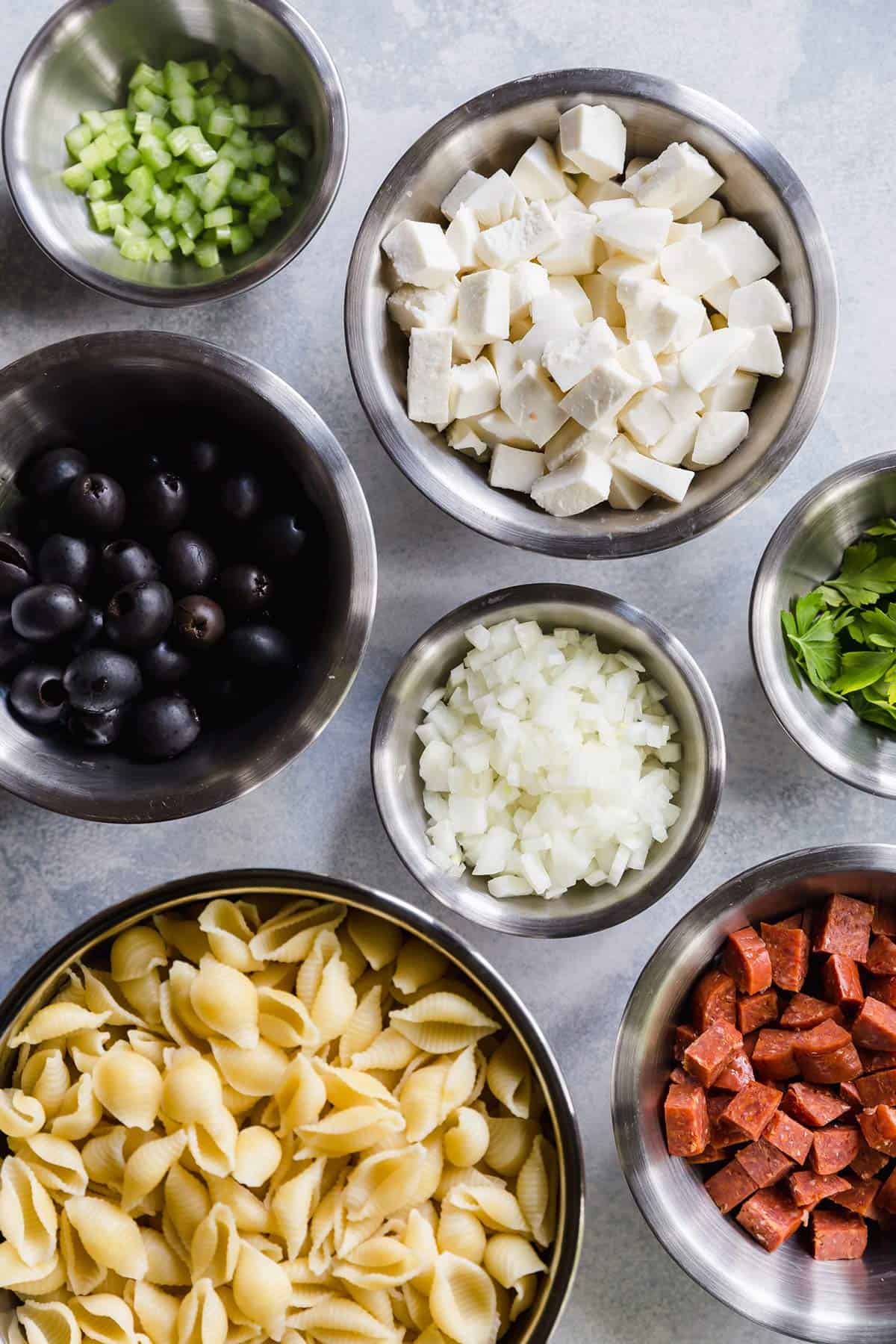 Ingredients for Italian pasta salad prepped in bowls on the counter.