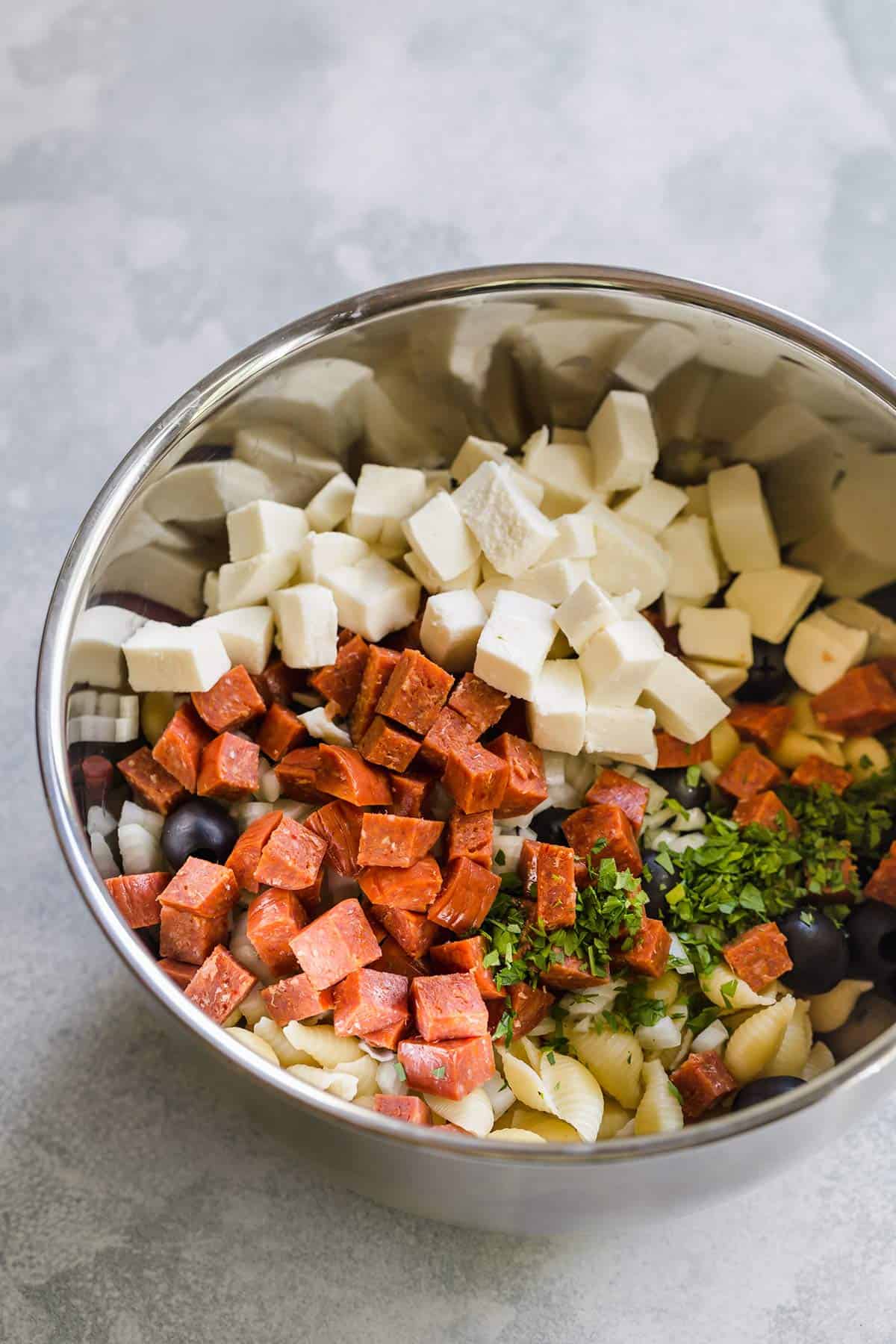 All of the ingredients for Italian pasta salad in a large mixing bowl.
