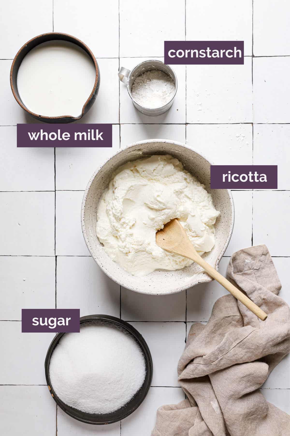 Ingredients for cannoli on a tile counter with purple labels.
