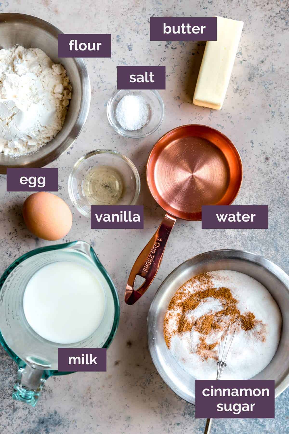 Ingredients for churros on a grey white counter with purple labels describing the ingredients. 
