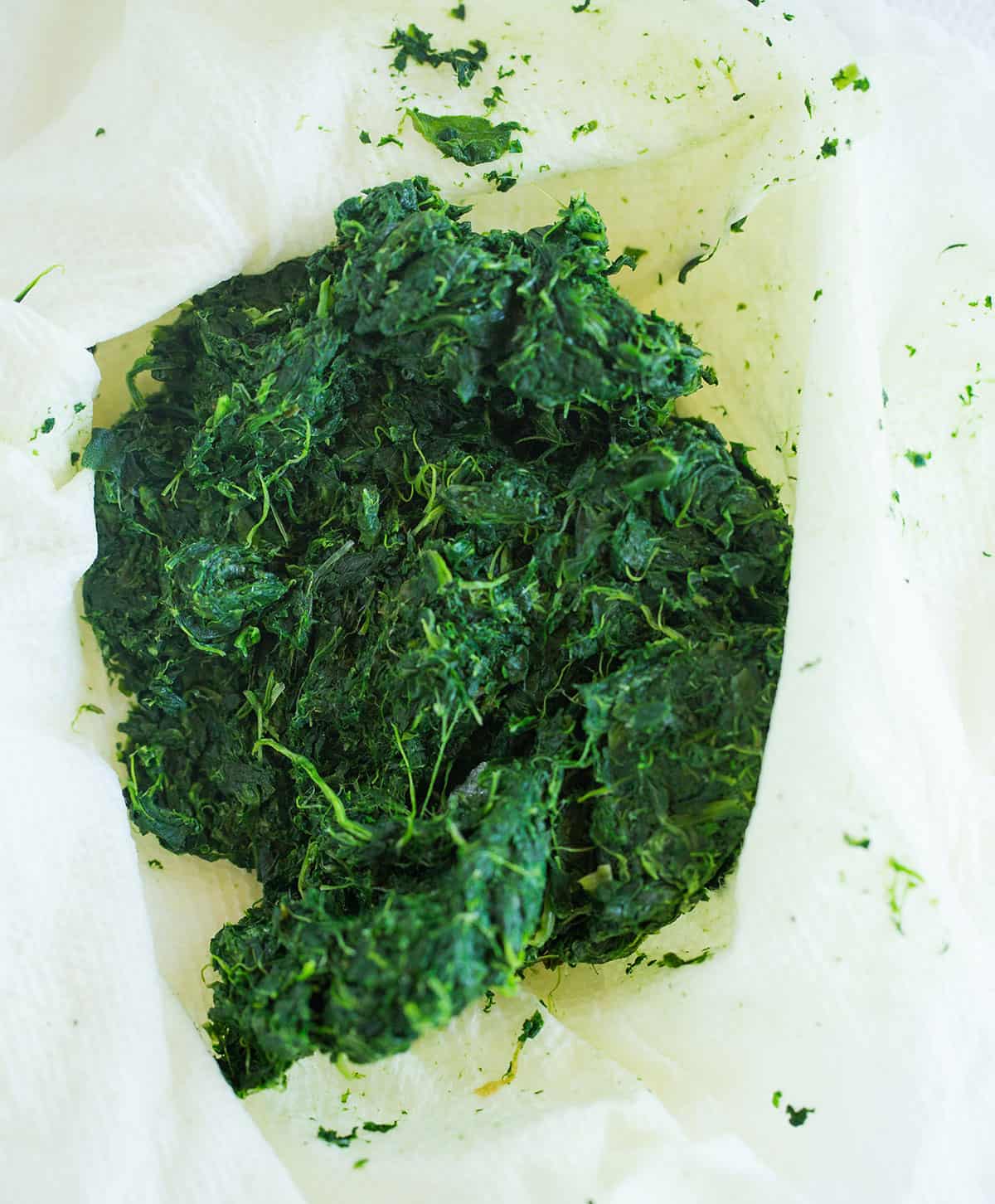 A dish towel with spinach after draining the moisture in a towel.