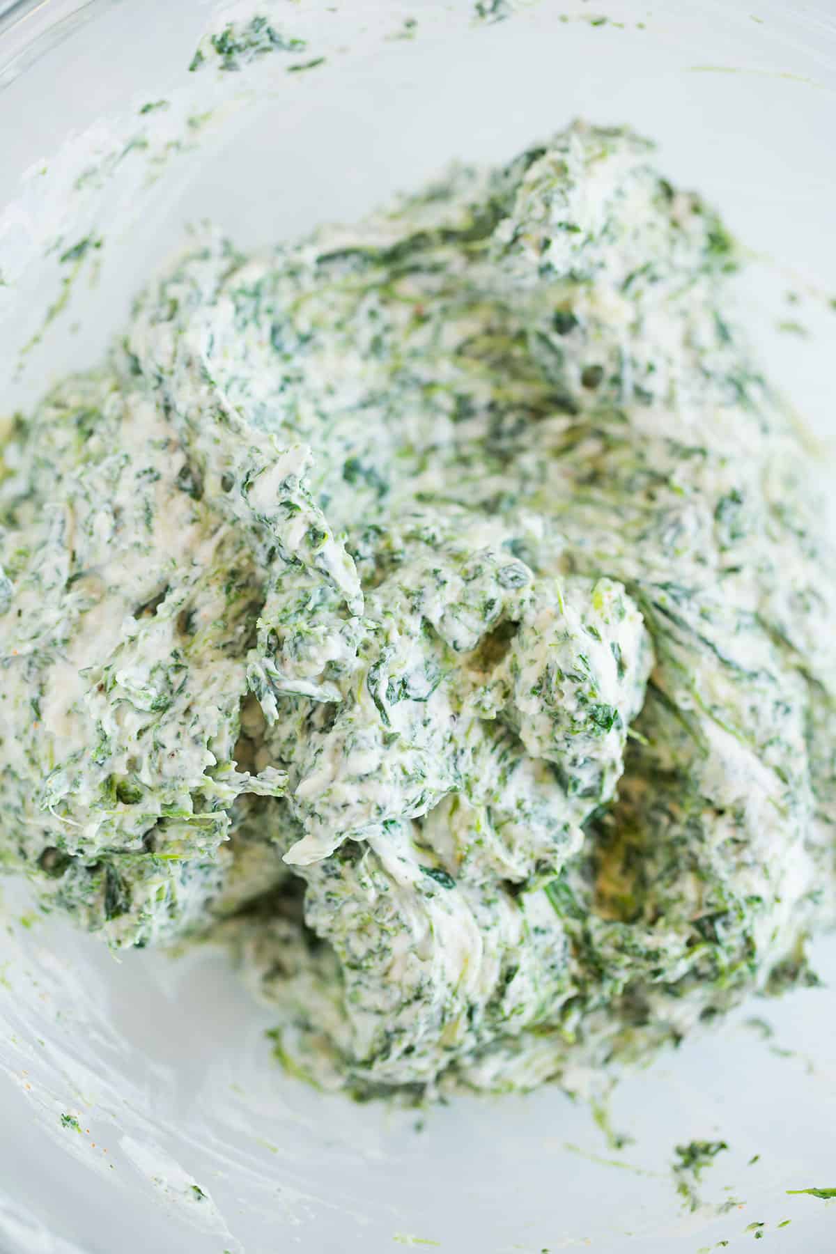 A glass bowl with creamy spinach dip.