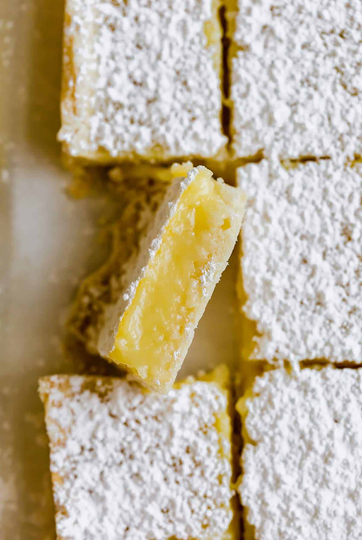 One lemon bar on its side next to other lemon bars.
